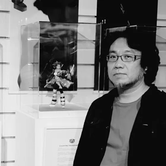 Portrait noir et blanc de Shinichiro Natsusaka devant une figurine